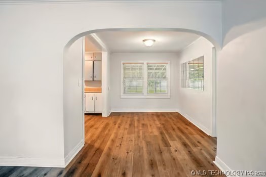1435 E Oak St, Cushing, OK 74023 - unfurnished dining area with arched walkways, wood finished floors, and baseboards