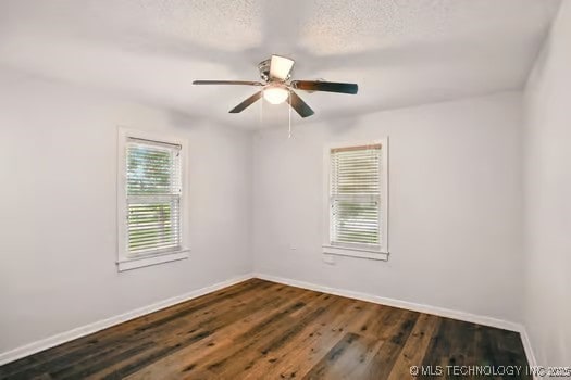 1435 E Oak St, Cushing, OK 74023 - spare room with baseboards, a ceiling fan, dark wood-type flooring, and a textured ceiling