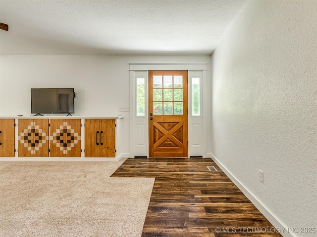 foyer with a textured wall, dark wood finished floors, and baseboards
