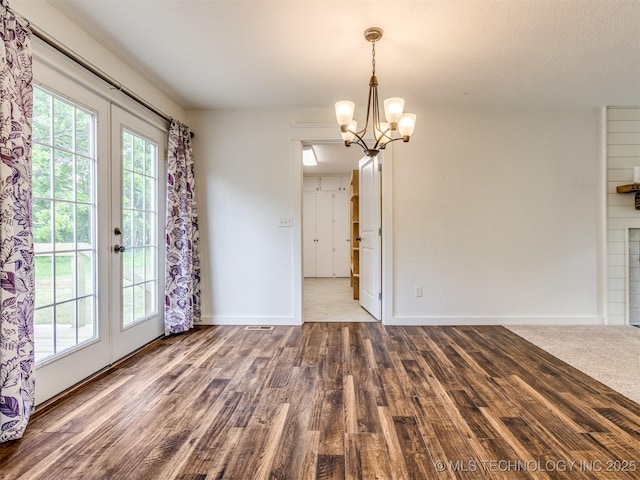 unfurnished dining area with wood finished floors, a chandelier, french doors, and baseboards