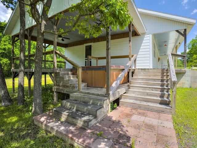 back of property featuring ceiling fan and stairs