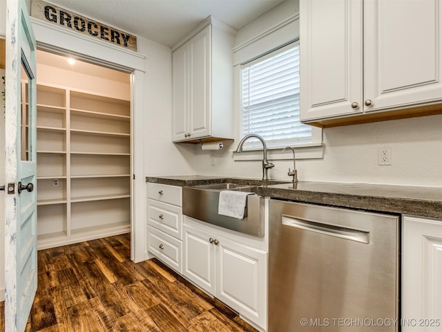 kitchen featuring stainless steel dishwasher, a sink, white cabinetry, dark wood-style floors, and dark stone counters