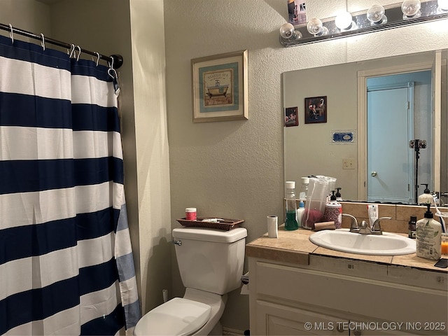 bathroom with a textured wall, toilet, vanity, and a shower with curtain