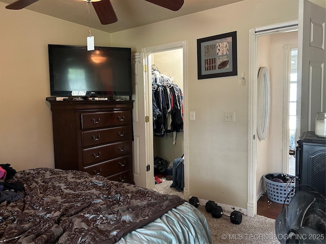 carpeted bedroom featuring a spacious closet, a closet, baseboards, and ceiling fan