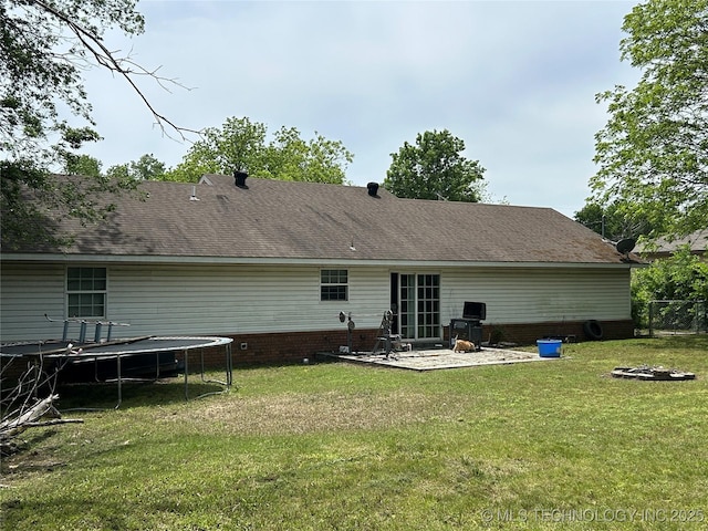 back of property with a trampoline, a patio, and a fire pit
