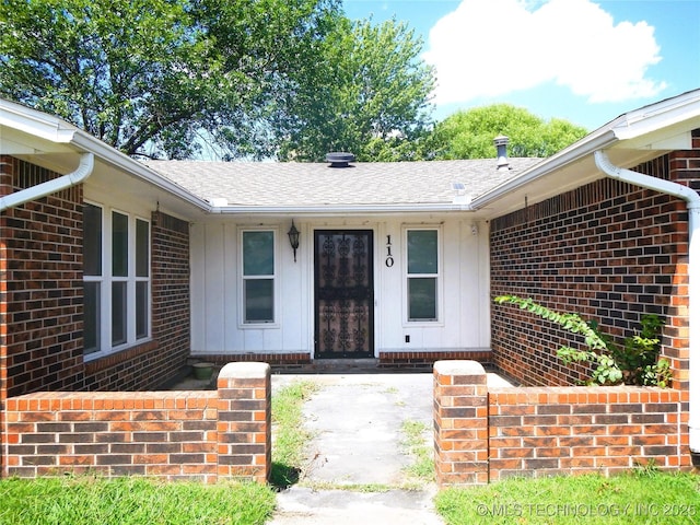 110 W 8th St, So Coffeyville, OK 74072 - property entrance featuring board and batten siding, a shingled roof, and brick siding