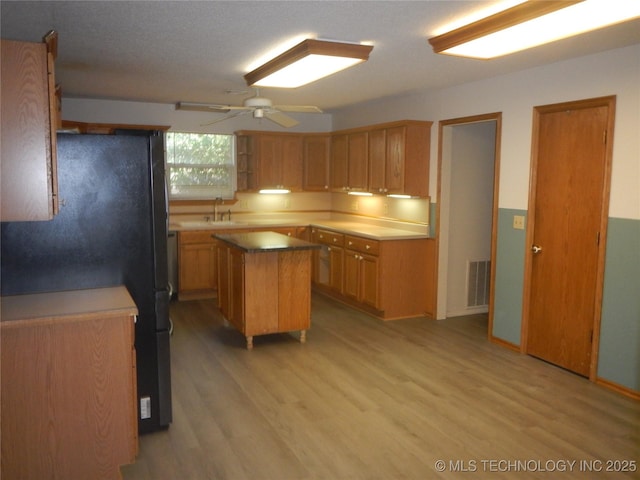110 W 8th St, So Coffeyville, OK 74072 - kitchen with freestanding refrigerator, light wood-style floors, a kitchen island, and ceiling fan