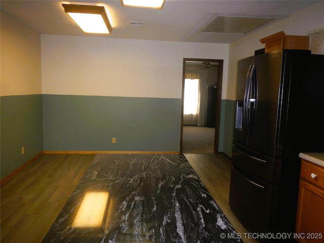 110 W 8th St, So Coffeyville, OK 74072 - kitchen with black fridge with ice dispenser, wood finished floors, baseboards, and brown cabinetry