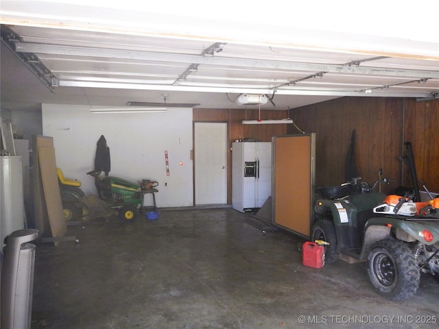 110 W 8th St, So Coffeyville, OK 74072 - garage featuring white refrigerator with ice dispenser, wooden walls, and a garage door opener