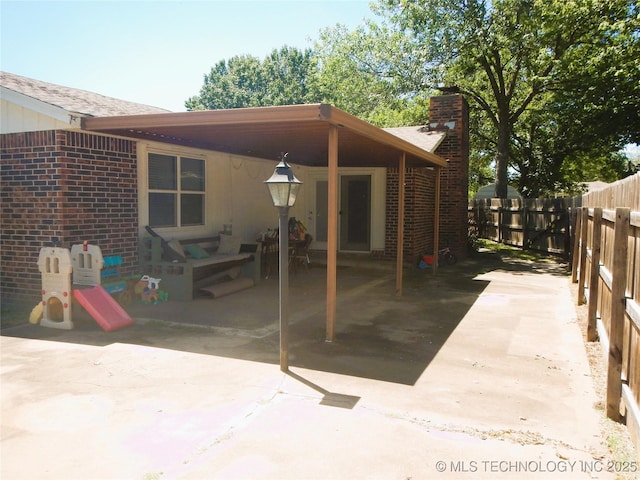110 W 8th St, So Coffeyville, OK 74072 - rear view of property with a chimney, fence, brick siding, and a patio