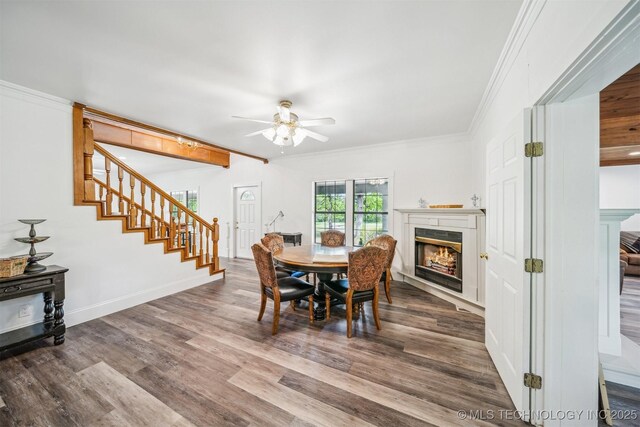 1001 County Road 2265, Skiatook, OK 74070 - dining room with a lit fireplace, stairs, a ceiling fan, wood finished floors, and crown molding