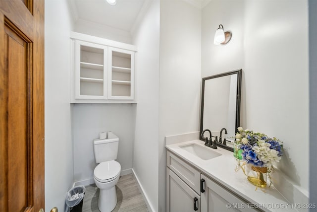 1001 County Road 2265, Skiatook, OK 74070 - half bath featuring ornamental molding, toilet, vanity, baseboards, and wood finished floors