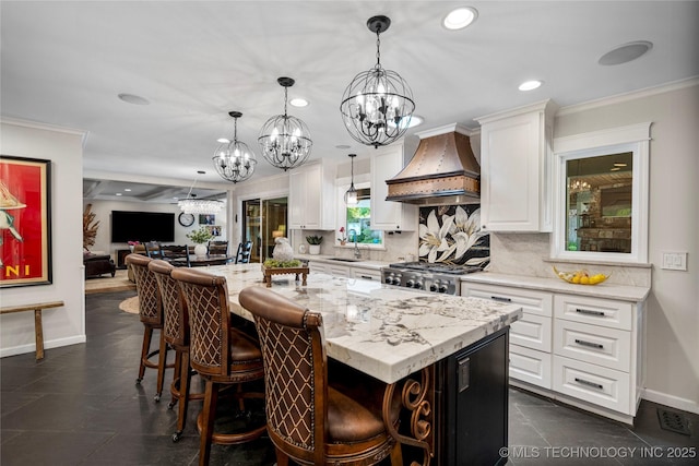 4728 S Atlanta Pl, Tulsa, OK 74105 - kitchen featuring premium range hood, a chandelier, tasteful backsplash, open floor plan, and a kitchen island with sink
