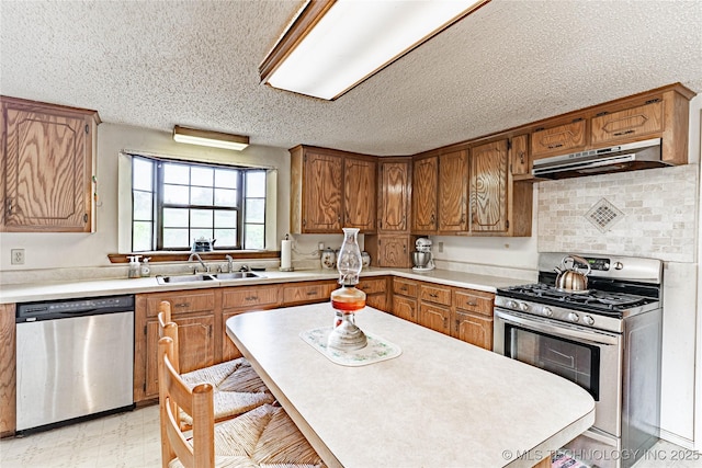 34047 W 191st St S, Bristow, OK 74010 - kitchen featuring appliances with stainless steel finishes, under cabinet range hood, a sink, brown cabinetry, and light countertops
