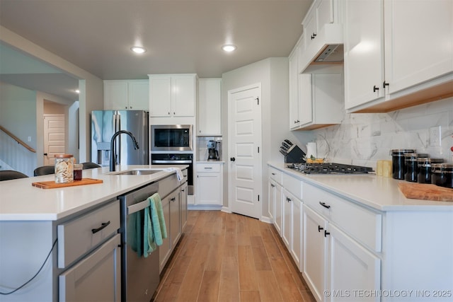 kitchen with stainless steel appliances, light wood-type flooring, light countertops, tasteful backsplash, and recessed lighting
