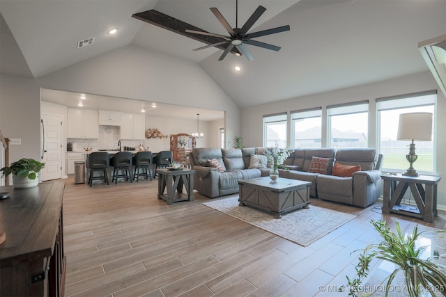 living area with ceiling fan, high vaulted ceiling, recessed lighting, and light wood finished floors