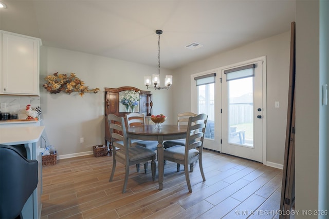 dining area with a chandelier, light wood finished floors, and baseboards