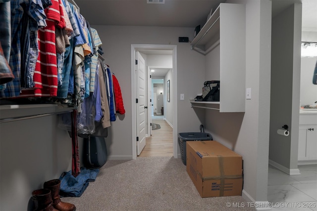 spacious closet featuring light marble finish floors