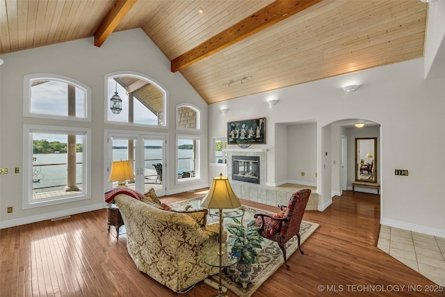 32290 S 630th Rd, Jay, OK 74346 - living area featuring arched walkways, beam ceiling, hardwood / wood-style floors, high vaulted ceiling, and a tiled fireplace