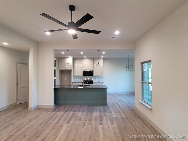 14474 N 50th W Ave, Skiatook, OK 74070 - kitchen featuring appliances with stainless steel finishes, white cabinetry, light wood-type flooring, dark countertops, and tasteful backsplash