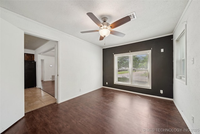 spare room with ceiling fan, wood finished floors, a textured ceiling, ornamental molding, and baseboards