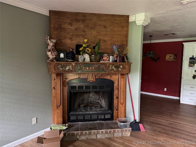 1509 Pawnee Ave, Hartshorne, OK 74547 - detailed view of wood finished floors, baseboards, ornamental molding, a fireplace with raised hearth, and a textured ceiling