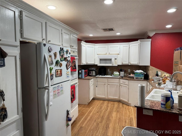 1509 Pawnee Ave, Hartshorne, OK 74547 - kitchen featuring white appliances, a sink, light wood finished floors, crown molding, and dark stone countertops