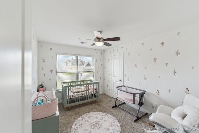 carpeted bedroom with a crib, ceiling fan, and baseboards