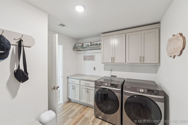 washroom featuring washer and clothes dryer, cabinet space, and light wood finished floors