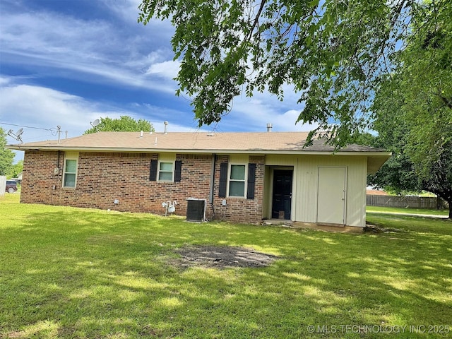 back of house with central AC unit, a yard, and brick siding
