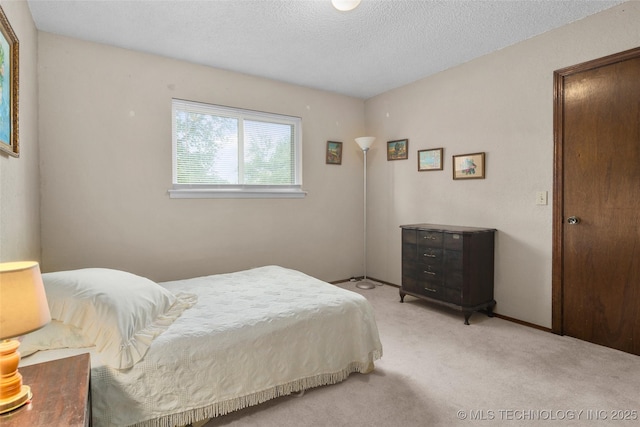 bedroom with light colored carpet and a textured ceiling