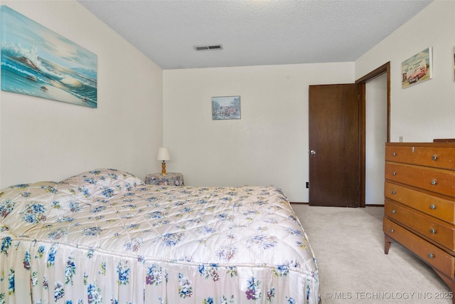 bedroom featuring light colored carpet and a textured ceiling