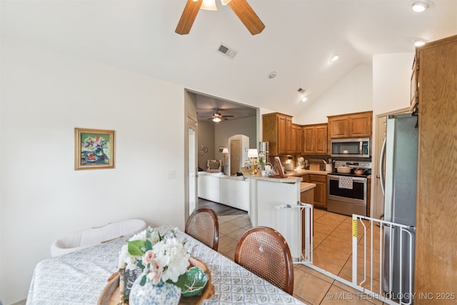 29901 E 137th Pl, Coweta, OK 74429 - kitchen with stainless steel appliances, ceiling fan, light tile patterned flooring, brown cabinetry, and high vaulted ceiling