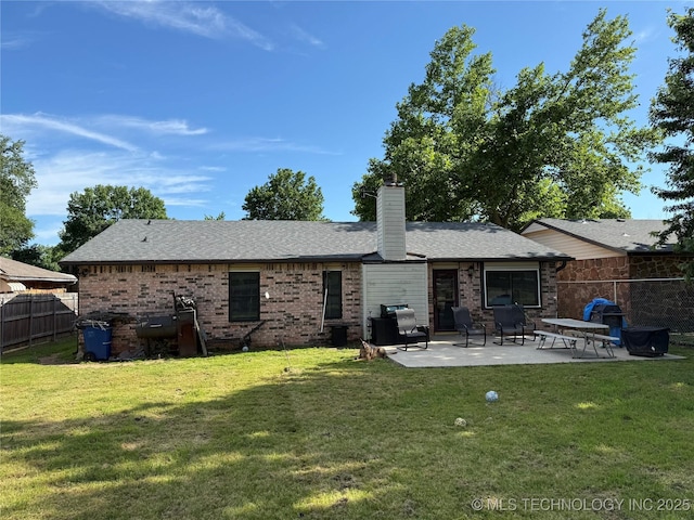back of house with a patio, brick siding, a chimney, and roof with shingles