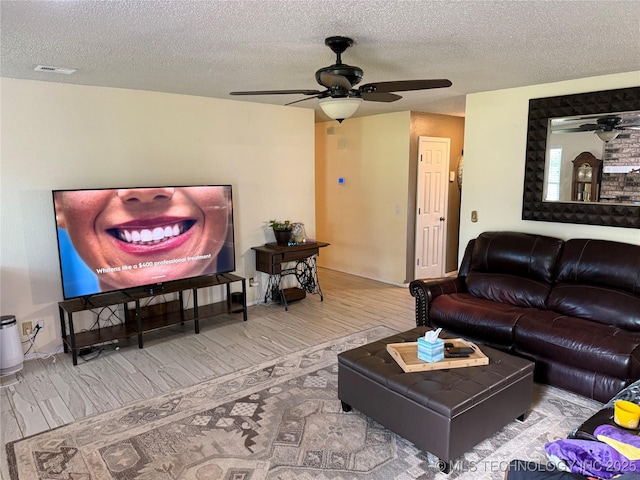 living area with wood finished floors, a textured ceiling, and ceiling fan