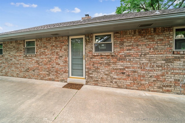 6123 E 53rd St, Tulsa, OK 74135 - doorway to property featuring a patio, brick siding, and a chimney