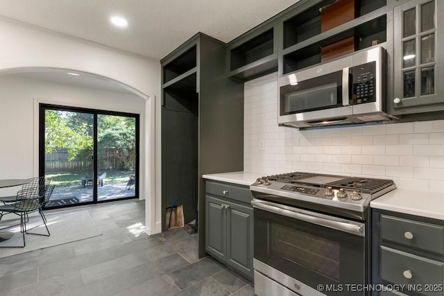 4907 S Boston Ave, Tulsa, OK 74105 - kitchen with appliances with stainless steel finishes, open shelves, arched walkways, gray cabinets, and backsplash