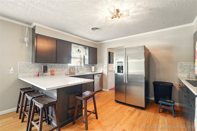 300 Michele, Calera, OK 74730 - kitchen with appliances with stainless steel finishes, a breakfast bar, a sink, a peninsula, and light wood finished floors