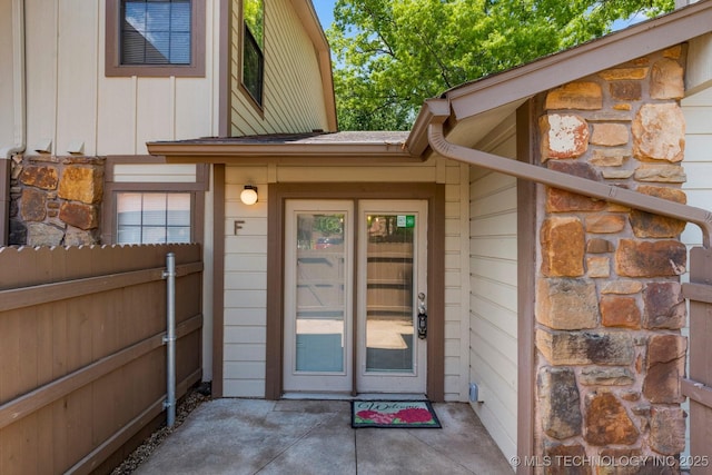 entrance to property with stone siding, fence, and a patio