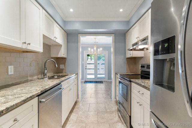 kitchen featuring appliances with stainless steel finishes, under cabinet range hood, a sink, ornamental molding, and a chandelier
