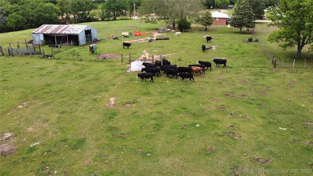 view of yard featuring an outbuilding, a view of countryside, fence, and an exterior structure