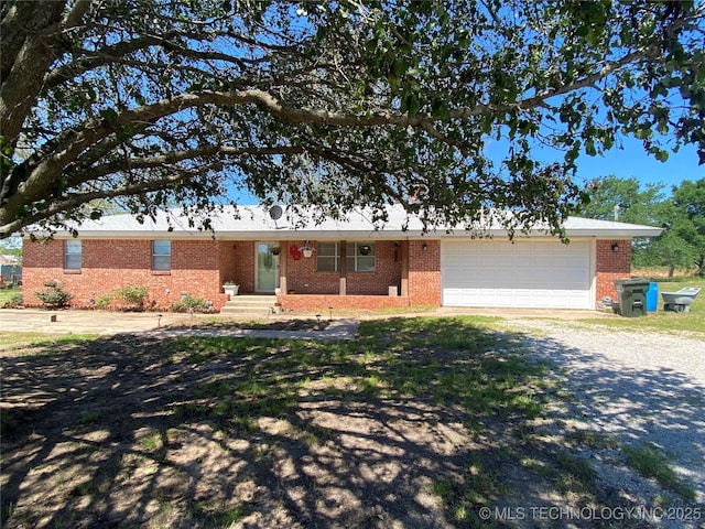 ranch-style house featuring gravel driveway, brick siding, and a garage