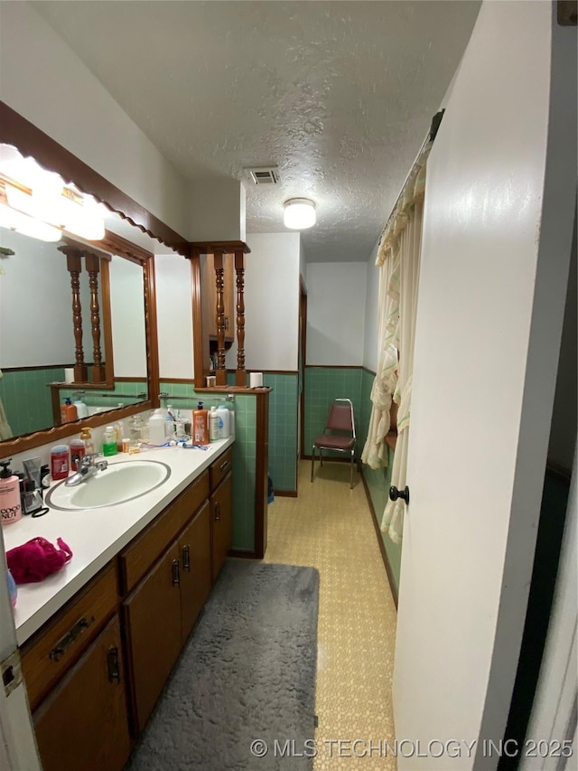 bathroom featuring a wainscoted wall, vanity, tile patterned floors, and a textured ceiling