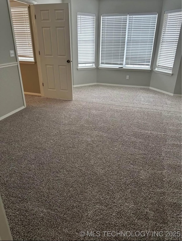 unfurnished room featuring baseboards, carpet flooring, and healthy amount of natural light