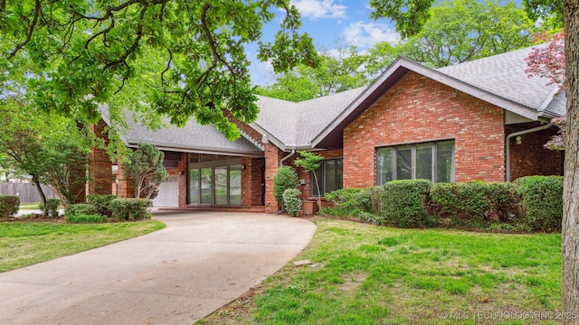 3219 S Birmingham Ave, Tulsa, OK 74105 - view of front of house featuring roof with shingles, brick siding, a front yard, and driveway