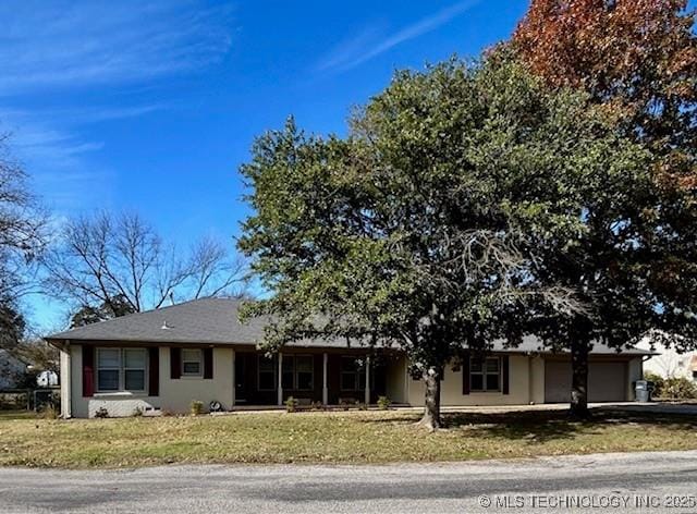 711 N SW, Ardmore, OK 73401 - view of front of house featuring an attached garage, a front lawn, stucco siding, and driveway