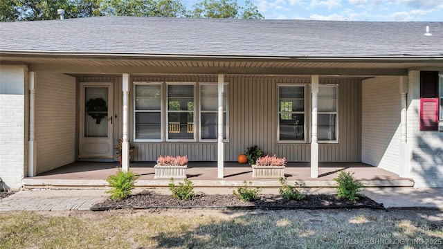 711 N SW, Ardmore, OK 73401 - doorway to property with a porch, brick siding, and roof with shingles
