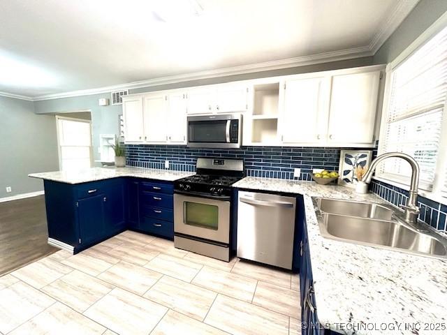 711 N SW, Ardmore, OK 73401 - kitchen featuring appliances with stainless steel finishes, a sink, a peninsula, crown molding, and white cabinets