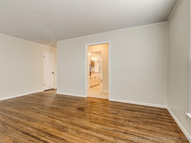 unfurnished room with crown molding, wood finished floors, and baseboards