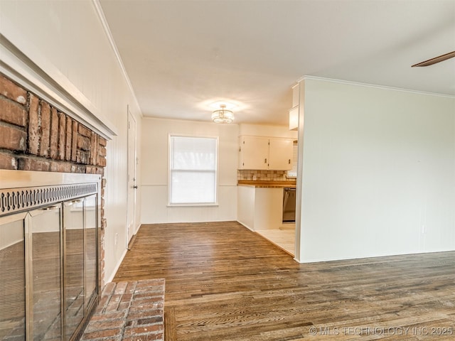 unfurnished living room featuring crown molding, wood finished floors, and a ceiling fan
